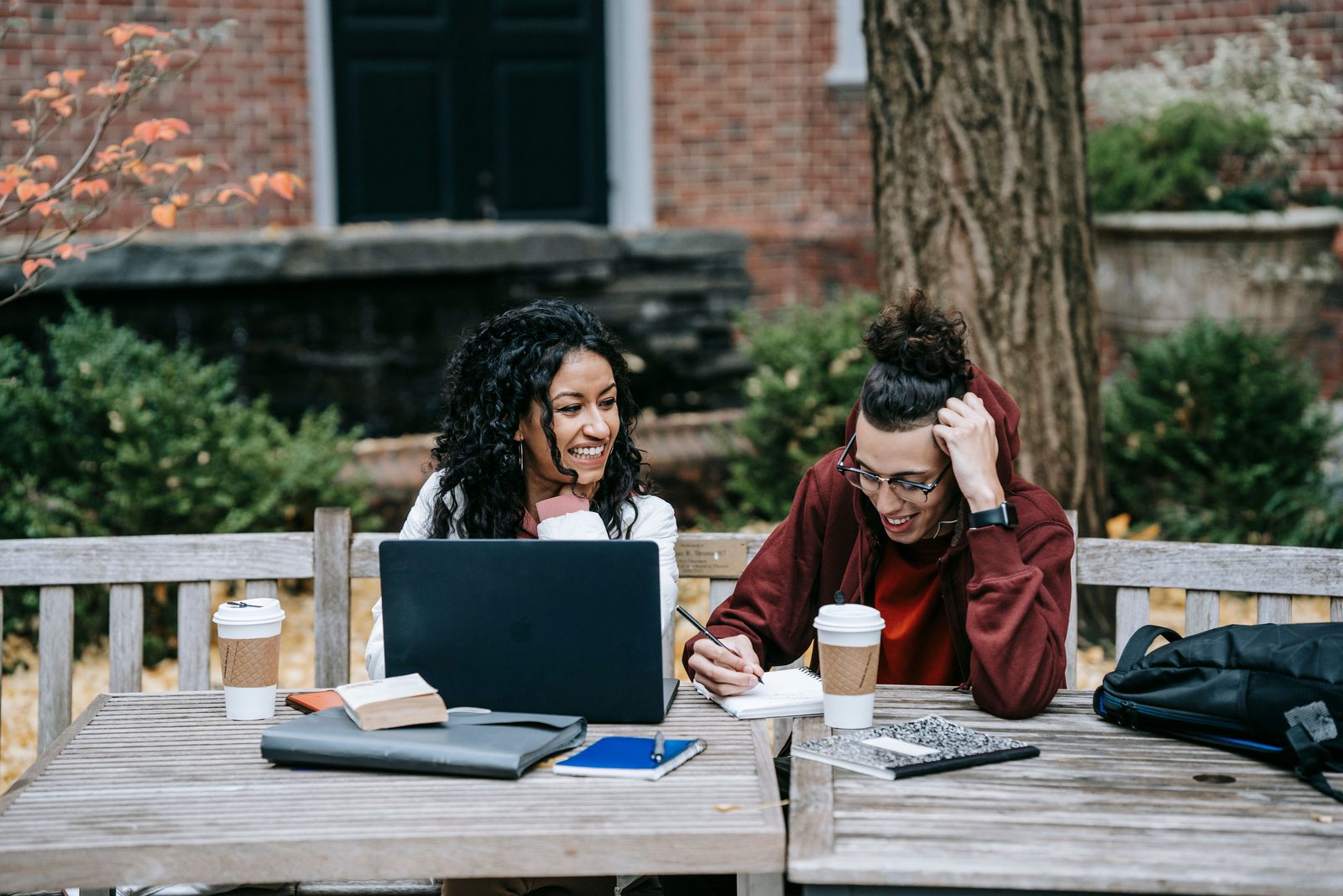 Two students working together outdoors with a laptop