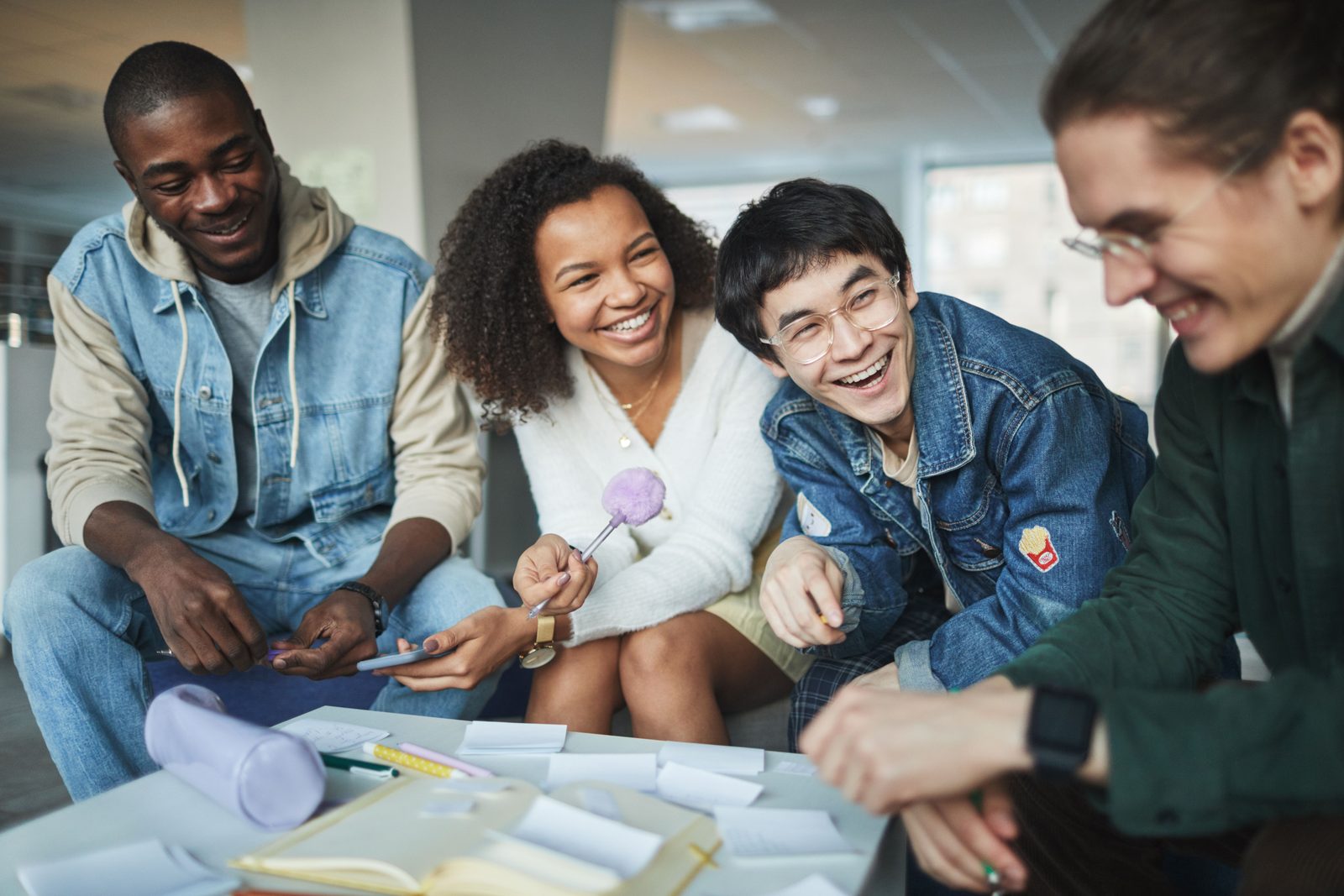A diverse group of young people laughing and working together
